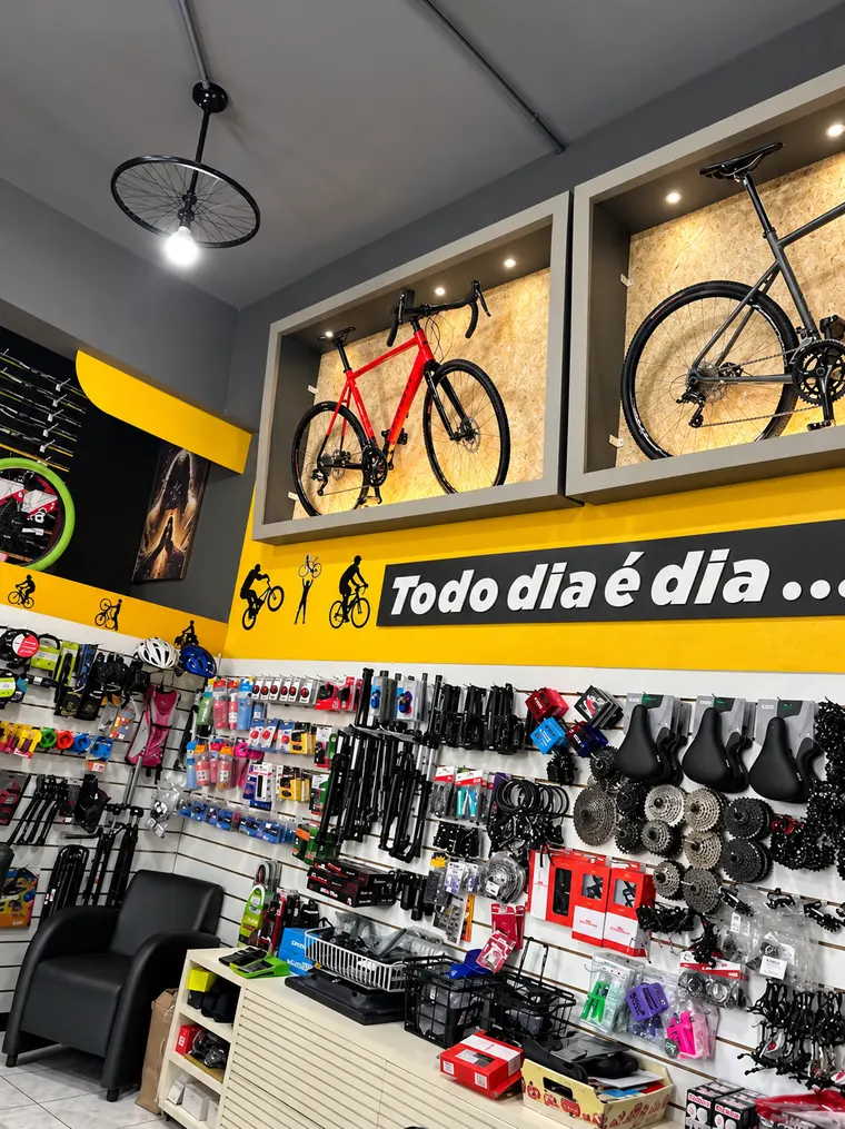 Parede amarela da loja com a frase Todo dia é dia, bicicletas em nichos e acessórios expostos