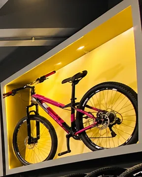 Mountain bike preta e rosa exposta em nicho amarelo iluminado